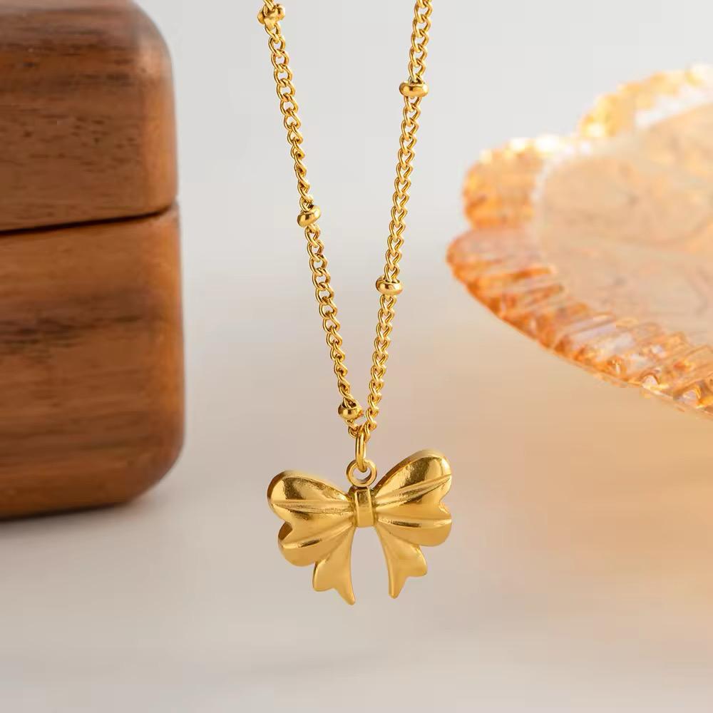 Elegant bow pendant necklace with a glossy gold finish and snake chain, ideal for everyday or party wear